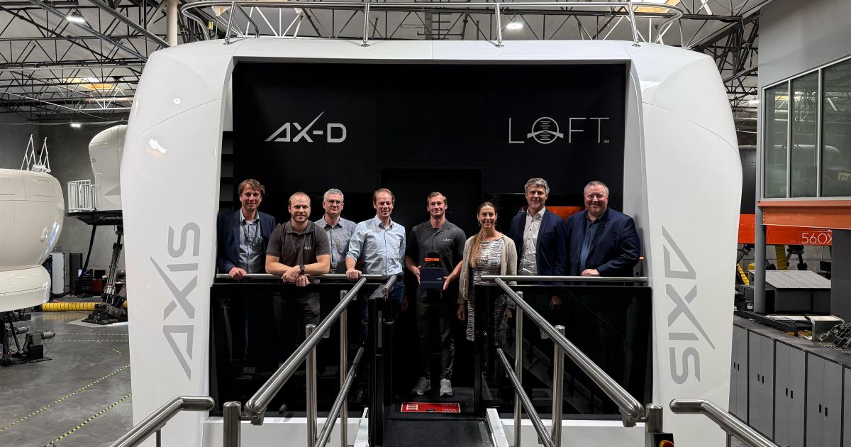 People standing in front of flight simulator in hangar 