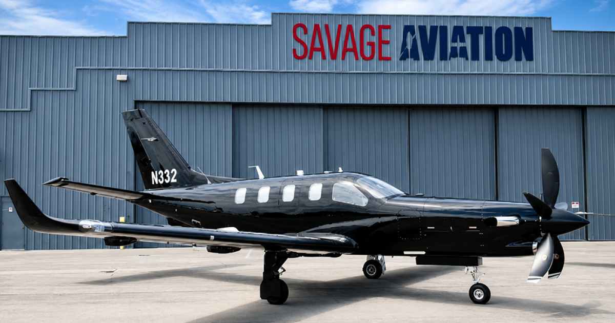 A Daher TBM 980 is parked on a ramp in front of Savage Aviation hangar