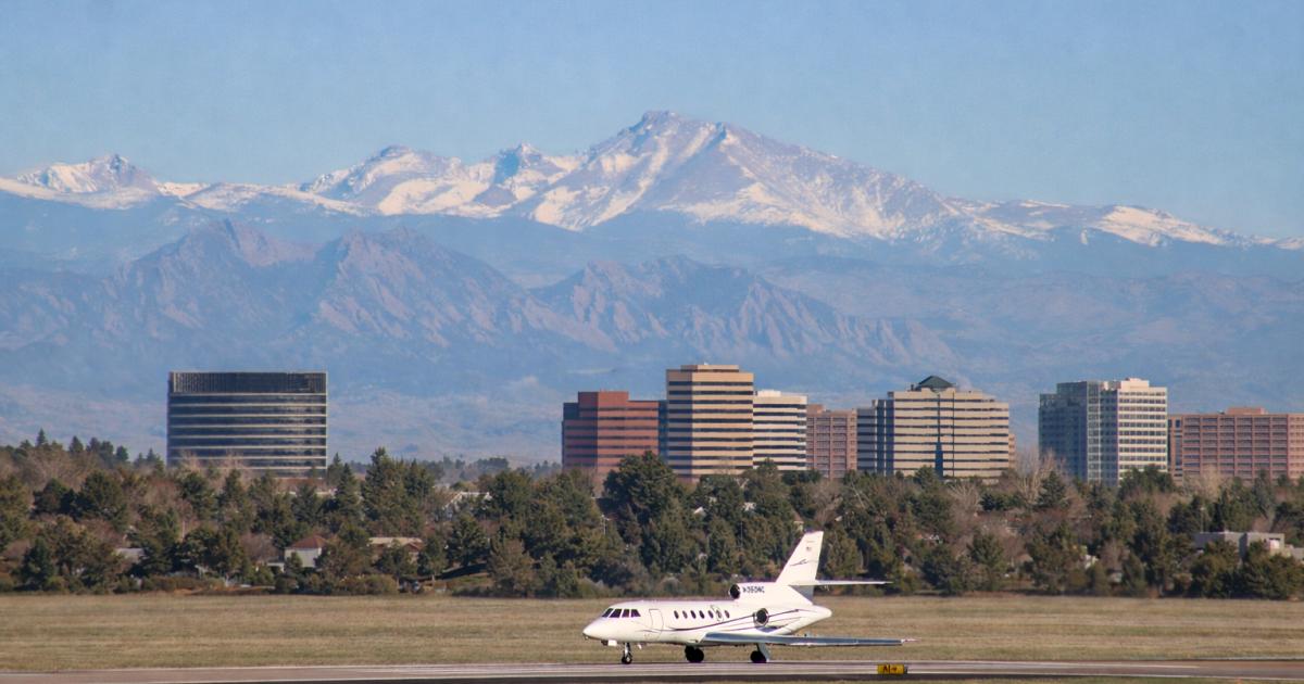 A jet taxiing at Englewood Aiport with buildings and the mountains in the background