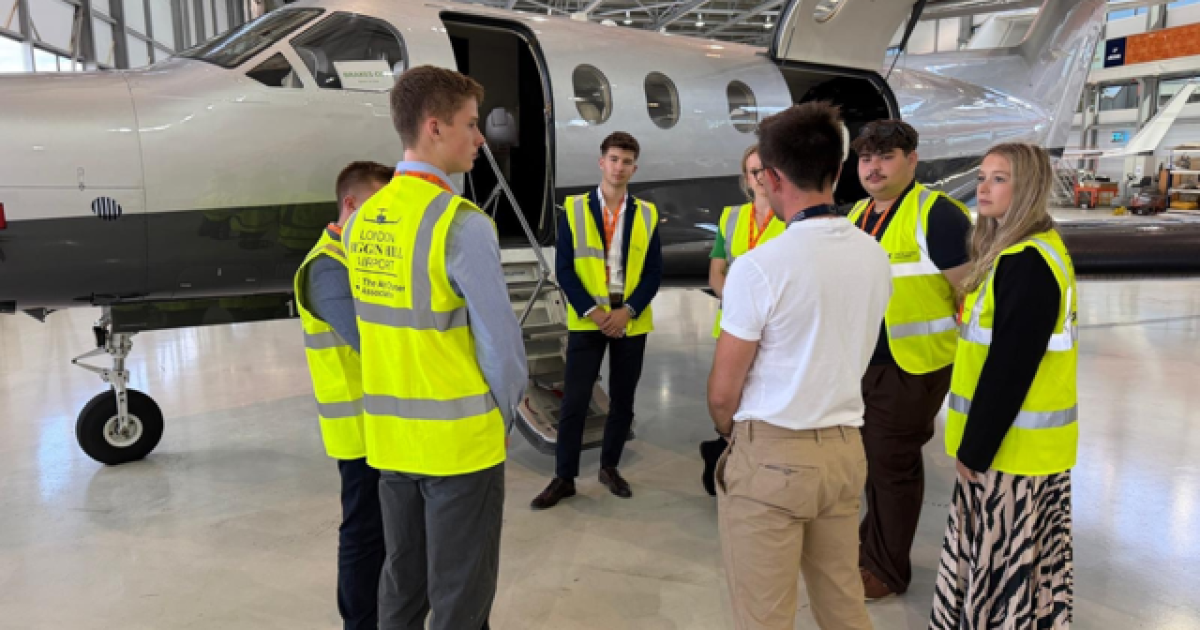 Students standing in hangar in yellow hi-viz jackets 