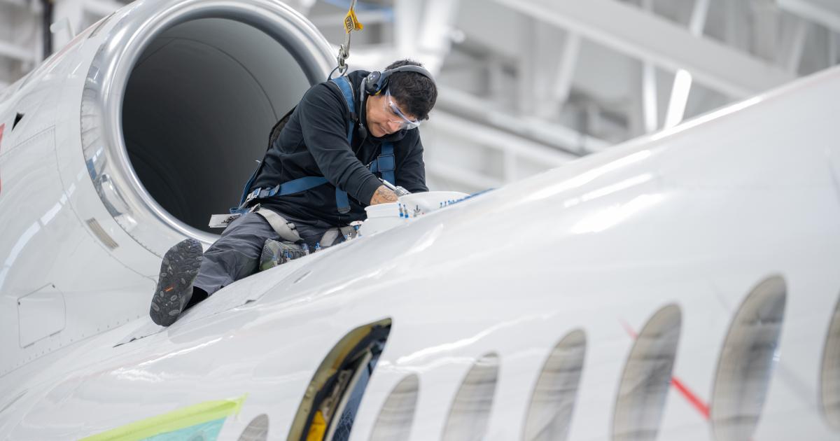 a mechanic works on inspecting a business jet in a maintenance hangar