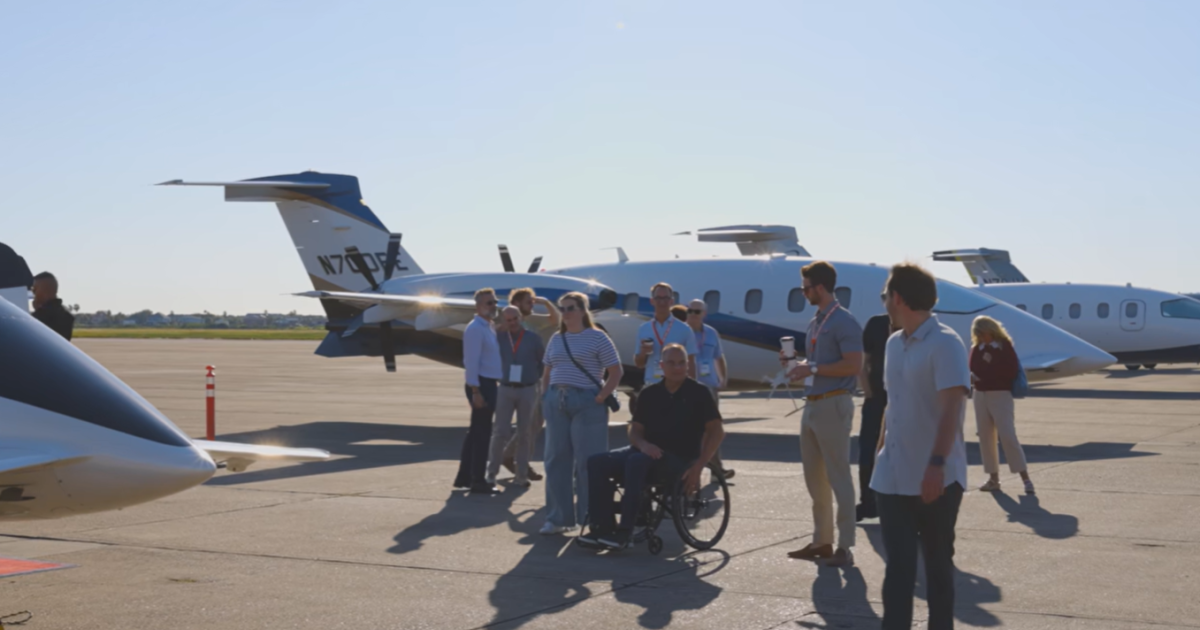Group of people on ramp, three aircraft behind 