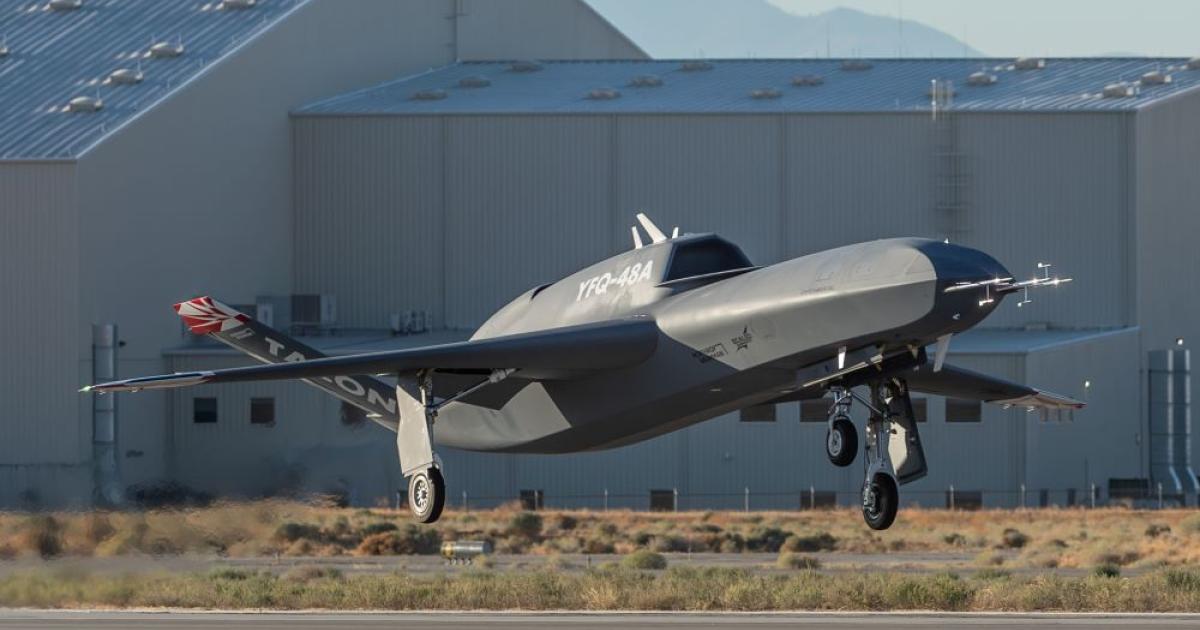 Uncrewed aircraft getting airborne from runway, hangar in background