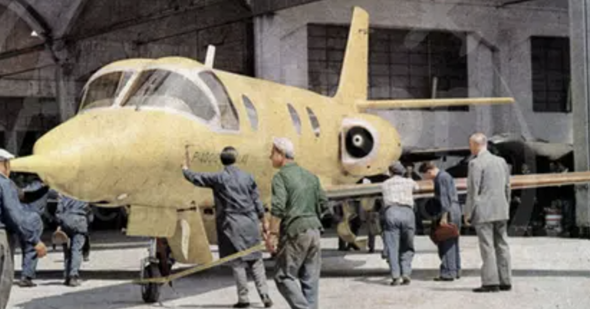 Unpainted Vespa Jet with workers in hangar 