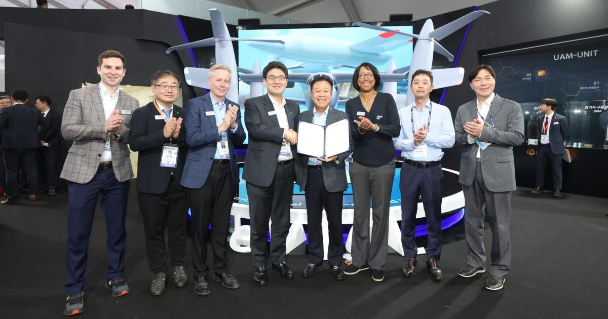 HeliKorea and Overair representatives pose with the signed letter of intent in front of a mockup of the Butterfly eVTOL aircraft