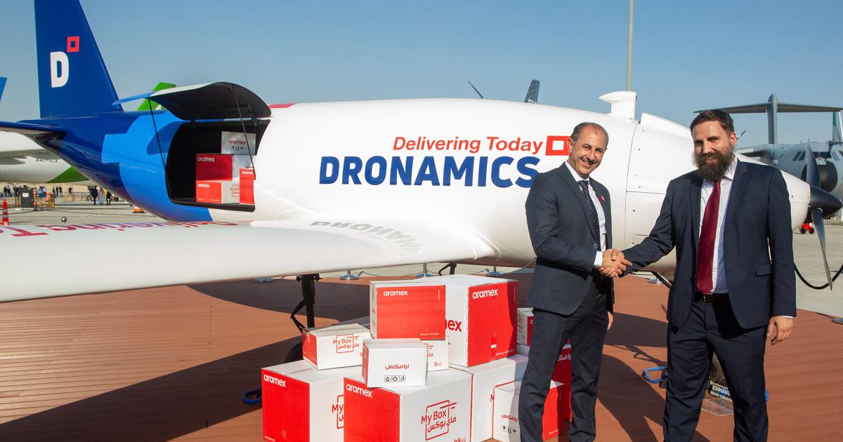 Aramex Chief Operating Officer Alaa Saoudi (left) and Dronamics co-founder and CEO Svilen Rangelov shake hands in front of a Dronamics Black Swan cargo drone after signing a letter of intent at the Dubai Airshow in November 2023