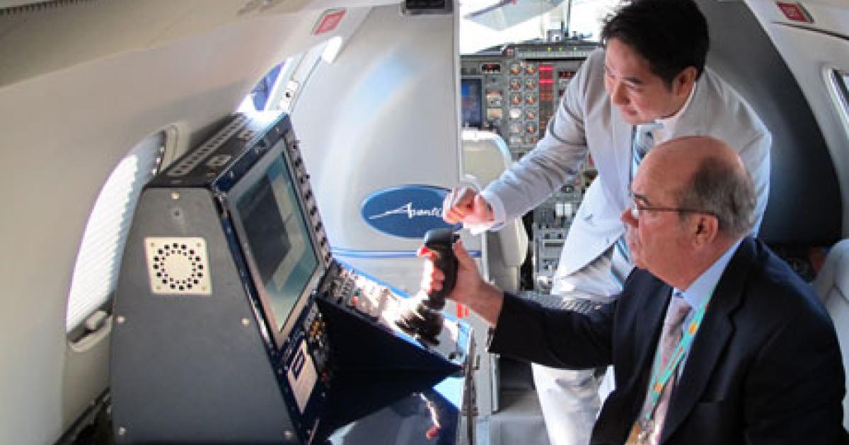 An employee of AdvAero (standing) demonstrates to Dr. John Johnson of Embry-Riddle Aeronautical University the ability of the specially equipped Piaggio P-180 Avanti to mimic a UAV flight control system. (Credit: Embry-Riddle Aeronautical University)