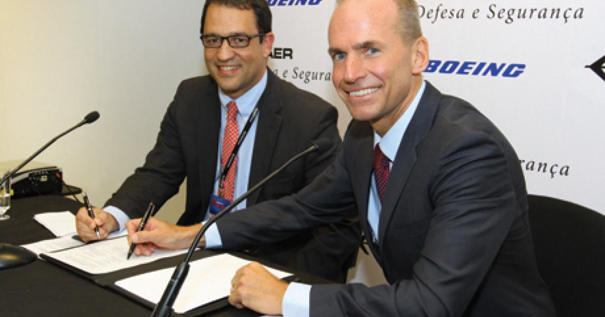 Signing a partnership pact are Embraer president of defense and security Luiz Carlos Aguiar and Boeing president and CEO of defense and securoty Dennis Mullenburg. (Photo: David McIntosh)
