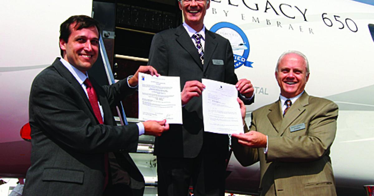 Displaying the appropriate paper work are (l to r) Embraer vice presidents Claudio Camelier, Luís Carlos Affonso and Ernest Edwards.