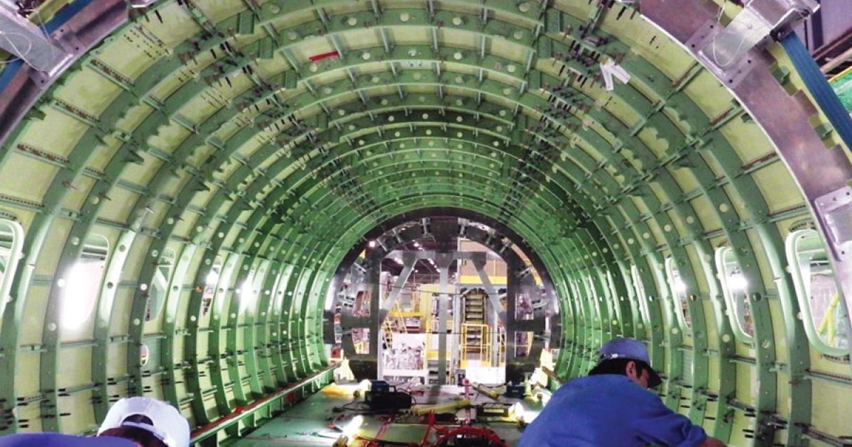 Technicians work on the MRJ’s center fuselage section at Mitsubishi Heavy Industries’ plant in Tobishima, Japan. Final assembly began last month.