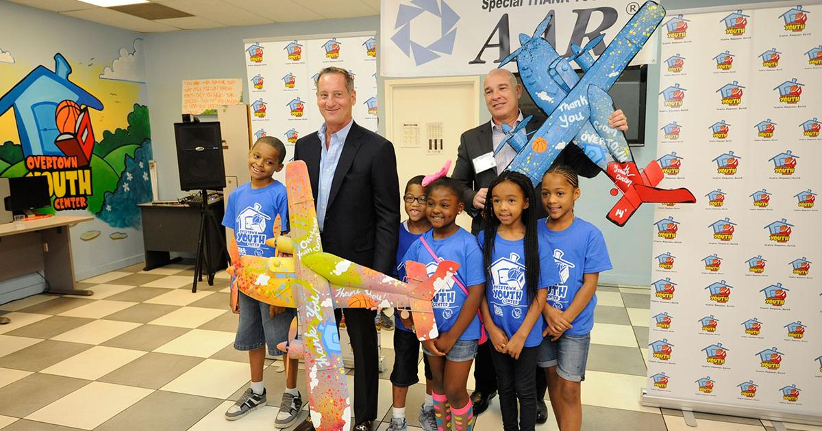 AAR CEO David Storch and Pastor Lopez, who heads AAR’s Landing Gear Repair Facility in Miami, receive airplanes painted by children at Overtown Youth Center in recognition of the time and money AAR is investing in the summer Stem program.