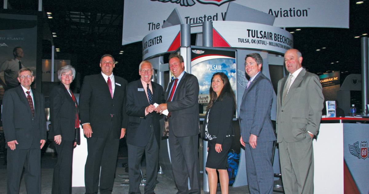 At the Phillips 66 booth here at NBAA 2014, Corporate Angel Network executive director Dick Koenig, center, accepts a $21,000 check from the fuel supplier.