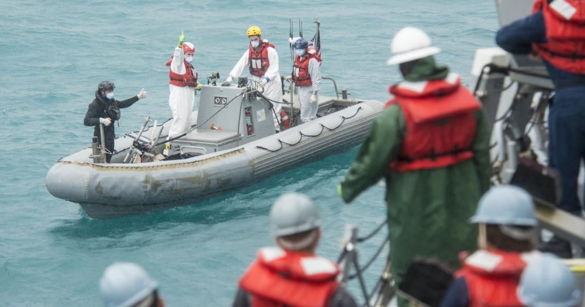 A U.S. Navy recovery team from the destroyer USS Sampson signals the boat deck crew while conducting operations in support of the Indonesian-led AirAsia flight QZ8501 search efforts.