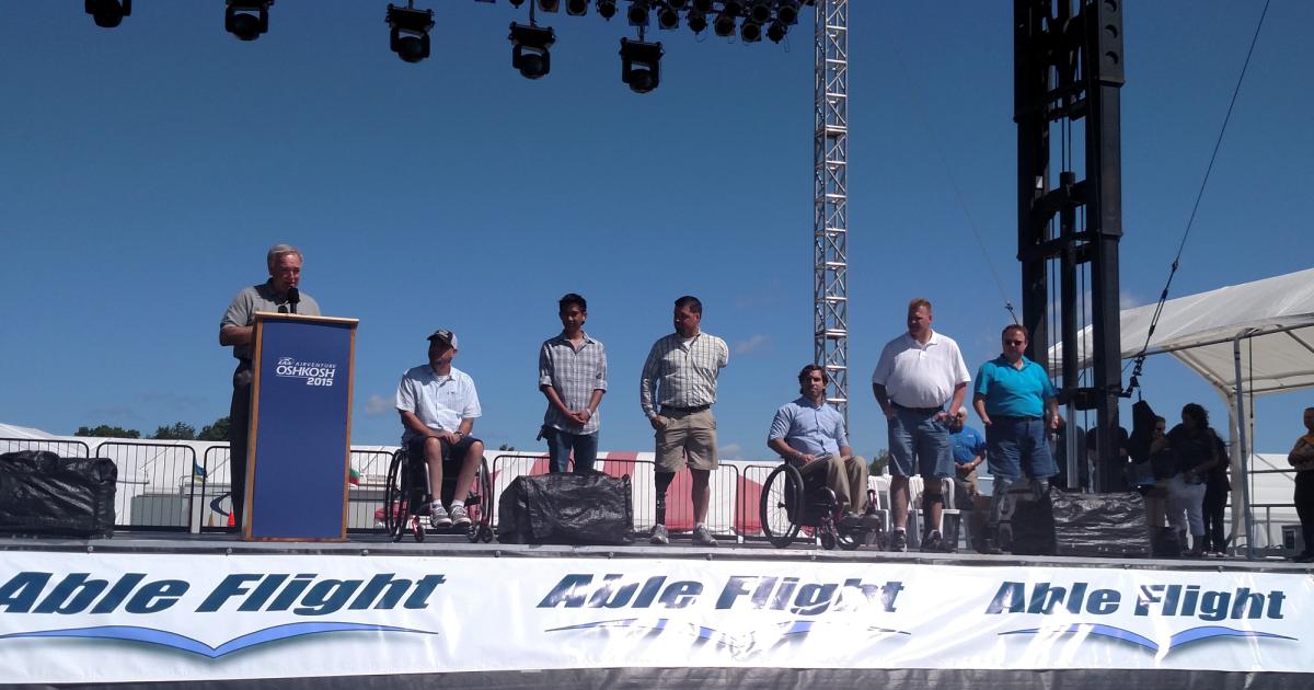 Able Flight awarded wings to six pilots this year at AirVenture. From left: Charles Stites (at podium), John Robinson, Raymart Tinio, Sgt. Adam Kisielewski, Stephen Carrier, Scot Abrams and Randy Green. 