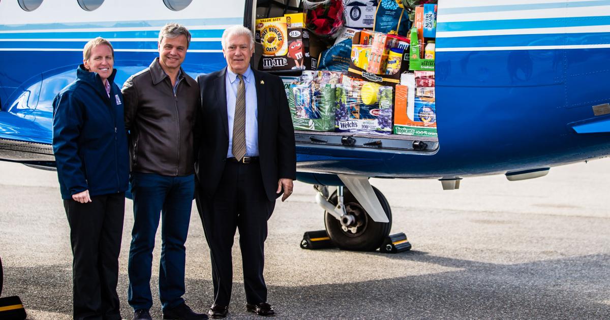 (L-R) Mel Gosselin, executive director of the New Hampshire Food Bank, PlaneSense president and CEO George Antoniadis and Manchester, N.H. Mayor Ted Gatsas prepare to unload some of the more than 7,000 lbs. of food collected by the fractional aircraft provider to benefit the Granite State's needy. (photo: PlaneSense)