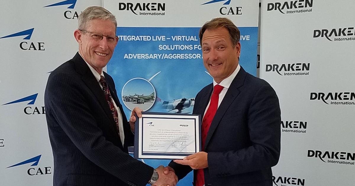Chuck Morant (l), CAE’s v-p of global strategy and business development, Defense and Security, shakes hands with Sean Gustafson, Draken’s v-p of business development, after the two inked a partnership deal calling for joint pursuit of new training and simulation opportunities.
