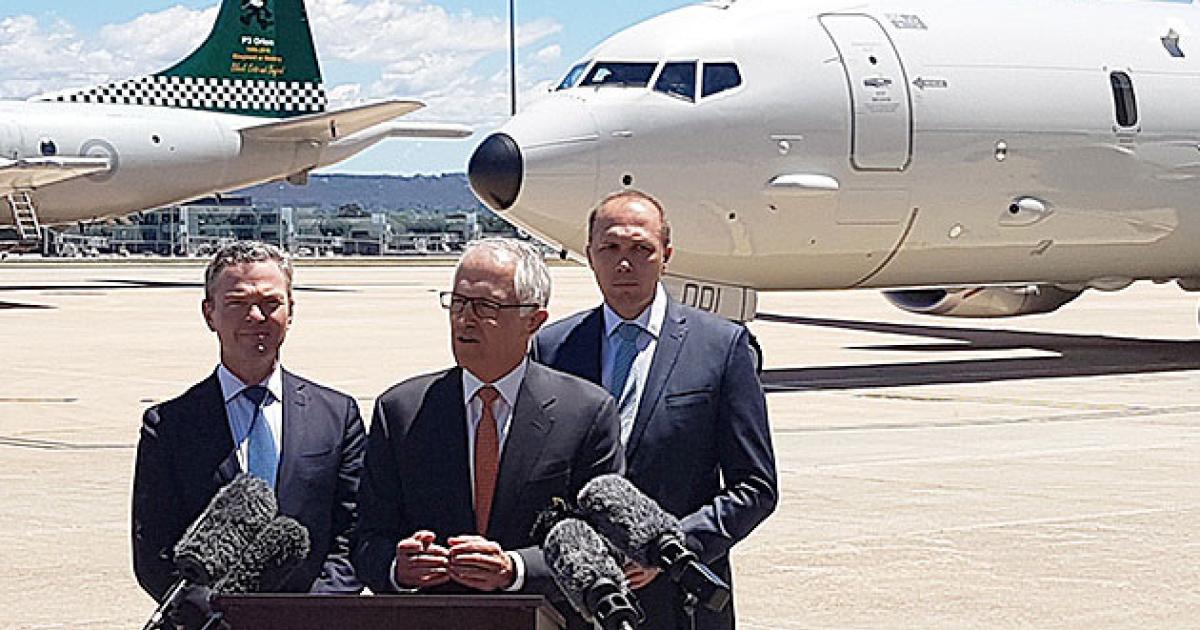 Australian Prime Minister Malcolm Turnbull (center) welcomed the first RAAF P-8A to Canberra, together with his defense and border police ministers. The Boeings will replace P-3 Orions (background). 
