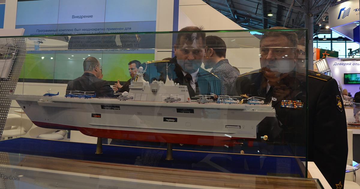 Officials inspect a model of the Priboi landing ship at the IMDS’2017 naval show in St Petersburg. (Photo: Vladimir Karnozov AIN)