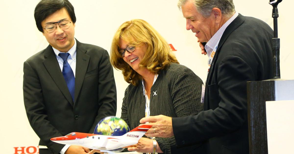 Honda Aircraft founding president and CEO Michimasa Fujino, left, helps hoteliers Kim, center, and Julian MacQueen celebrate the completion of their “Around the World in 80 Stays” tour. The couple circumnavigated the globe in their new HondaJet. PHOTO: DAVID McINTOSH