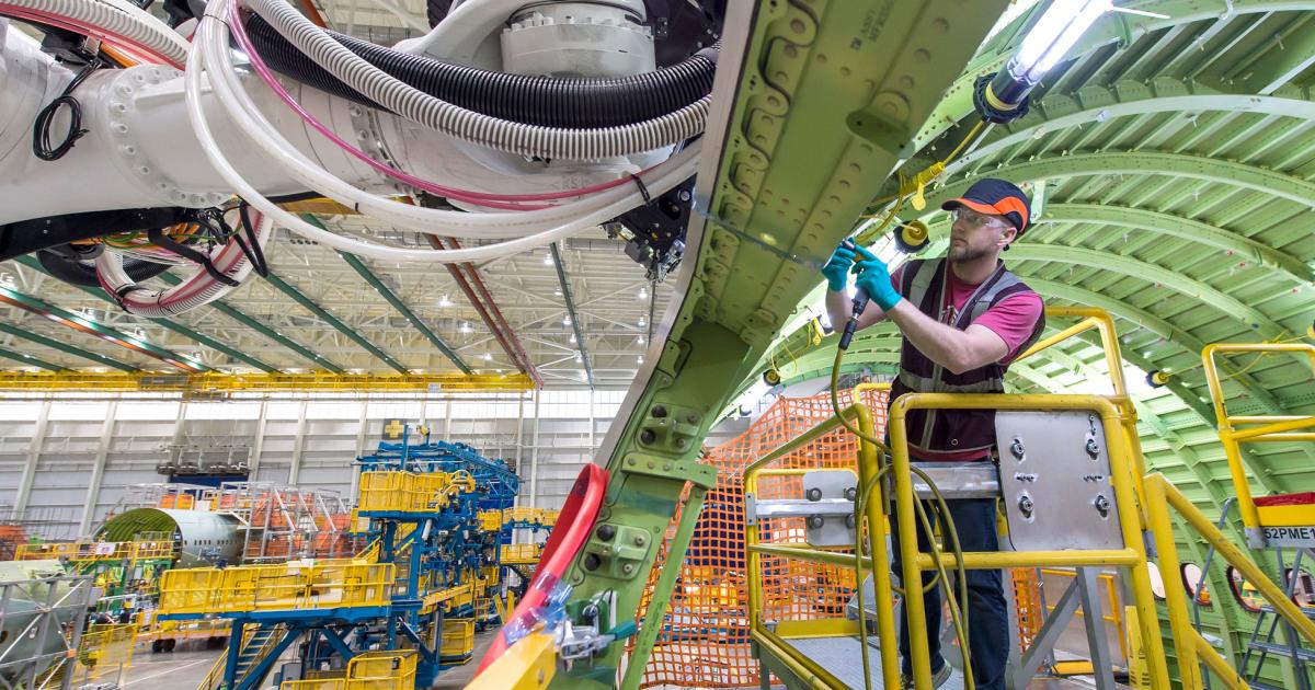 A Boeing employee prepares a robot to begin installing a fastener into the first production 777X wing spar at the company’s composite wing center in Everett, Washington. 