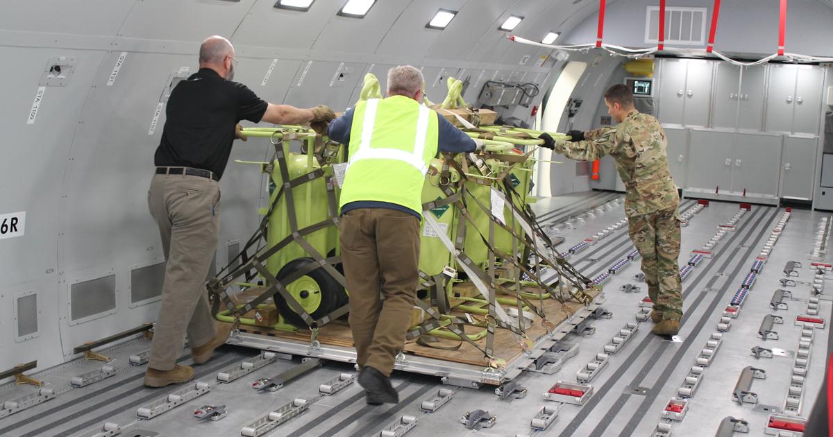 Instructors move a pallet across the roller floor of the KC-46 fuselage trainer at McConnell. Loadmaster instruction for KC-46 boom operators is being provided by Air Force and FlightSafety International personnel. (photo: Jerry Siebenmark)