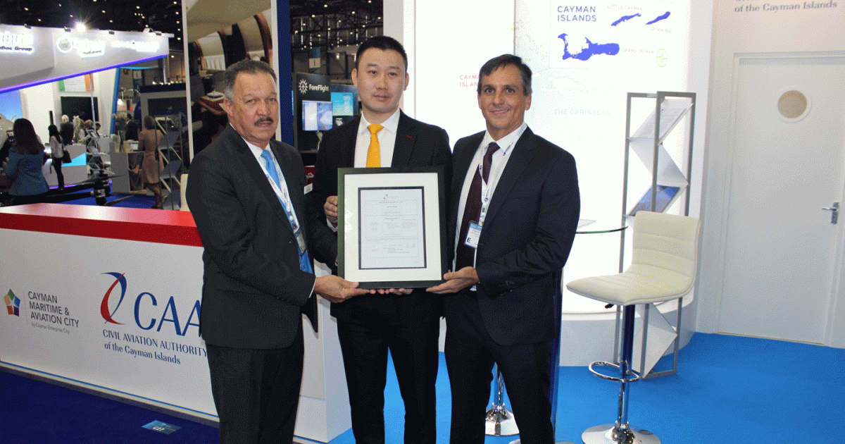 P.H. Richard Smith, director-general, Civil Aviation Authority of the Cayman Islands (left) presents AOC to Y.J. Zhang (center), president of HK Bellawings along with Charles Kirkconnell, CEO 
of Cayman Enterprise City.