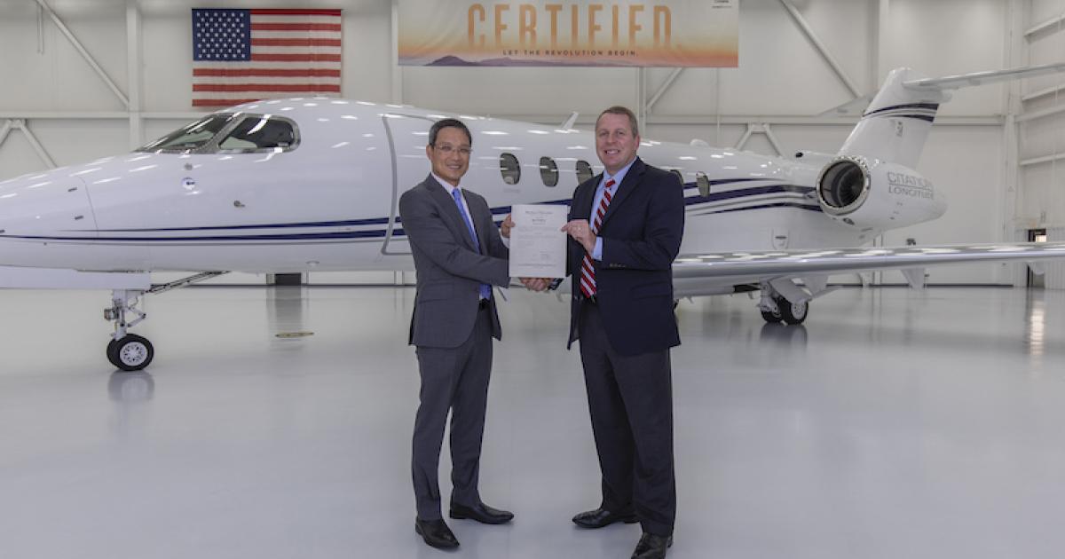 Paul (Vu) Nguyen, acting manager of the FAA's Wichita ACO branch, presents Textron Aviation CEO Ron Draper with the Citation Longitude's type certificate. (Photo: Textron Aviation)