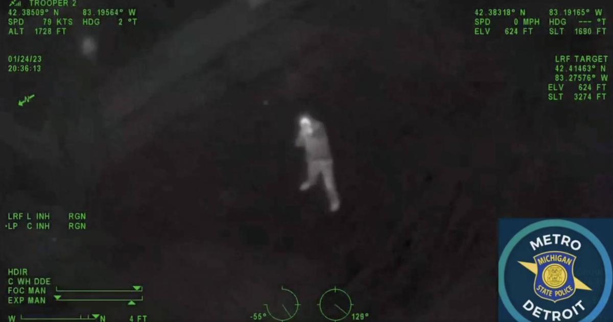 night vision mode view of man on ground pointing long gun at Michigan State Police helicopter