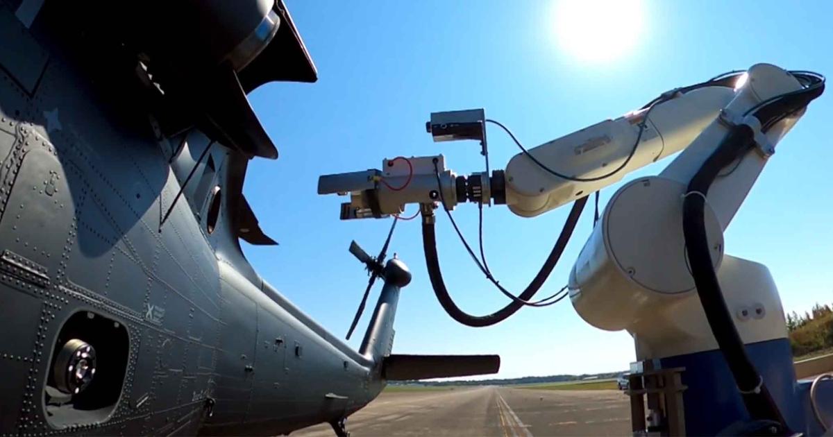 A robotic refueler is pictured next to a helicopter