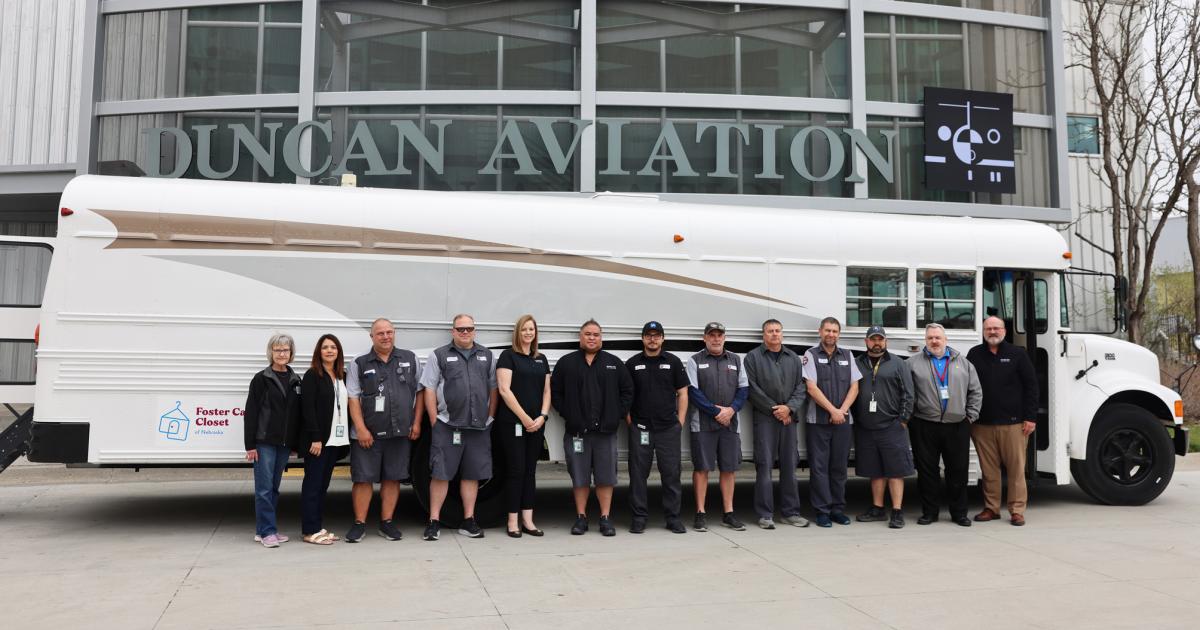 Duncan Aviation workers pose with charity bus they refurbished