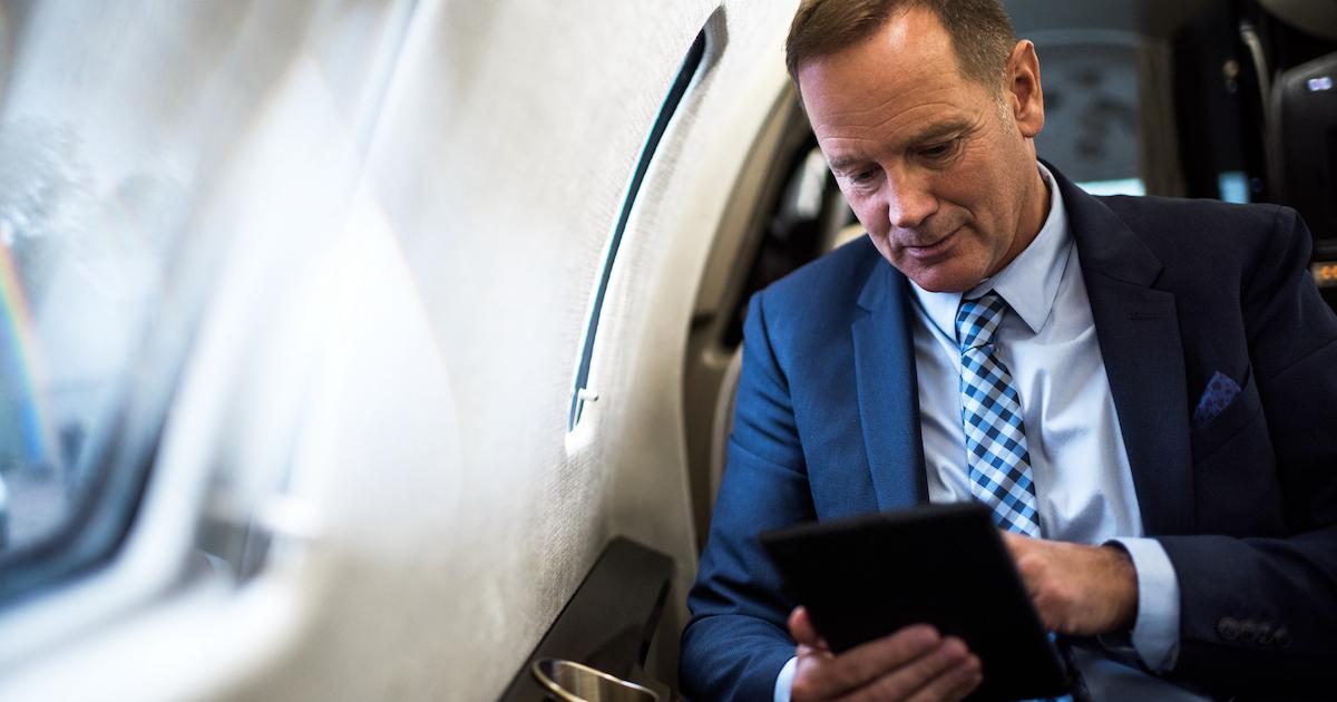Businessman on iPad in business jet cabin