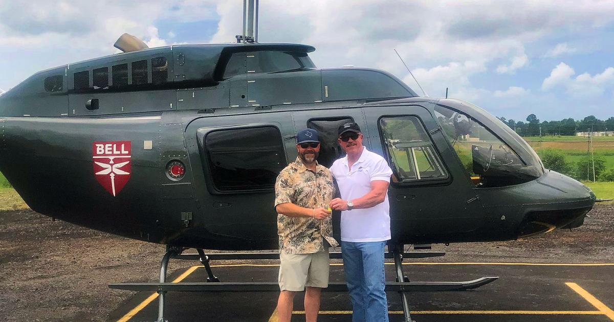 Michael Bashlor, the Managing Partner at Meridian Helicopters (right) handing keys of refurbished Bell 206L4 to Kevin Reed with helicopter in background. 