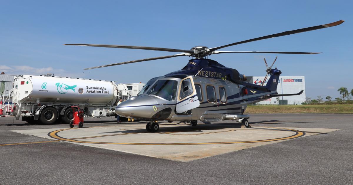 Airbus AW139 helicopter on helipad with sustainable aviation fuel refueling truck parked next to it