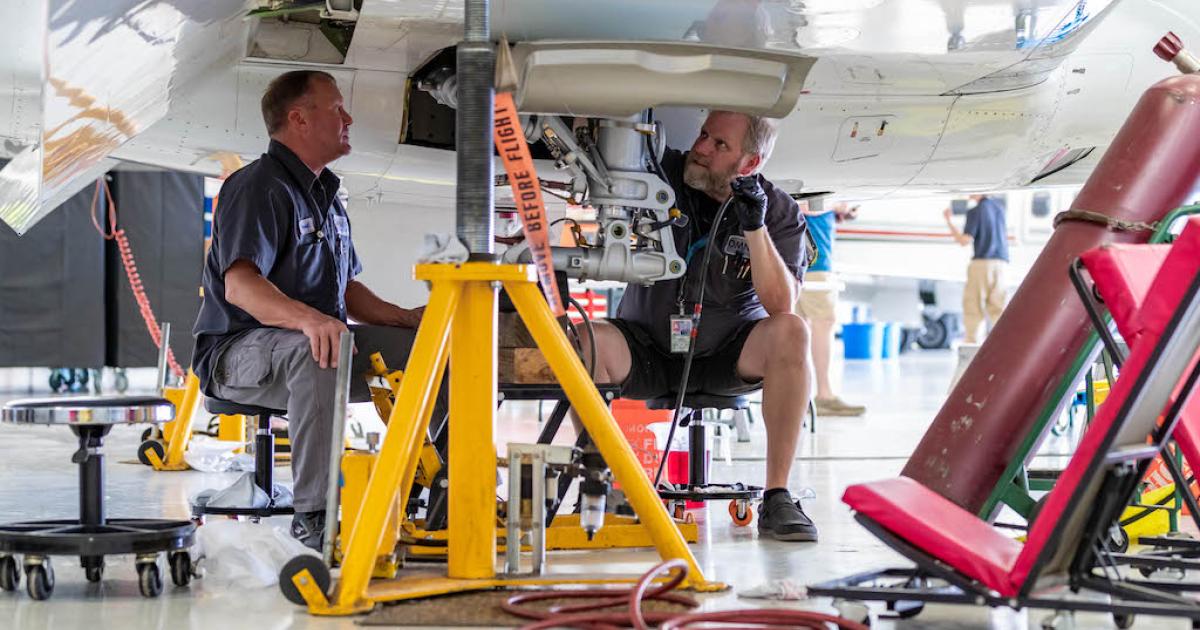 Omni Aircraft Maintenance technicians at work underneath aircraft wing