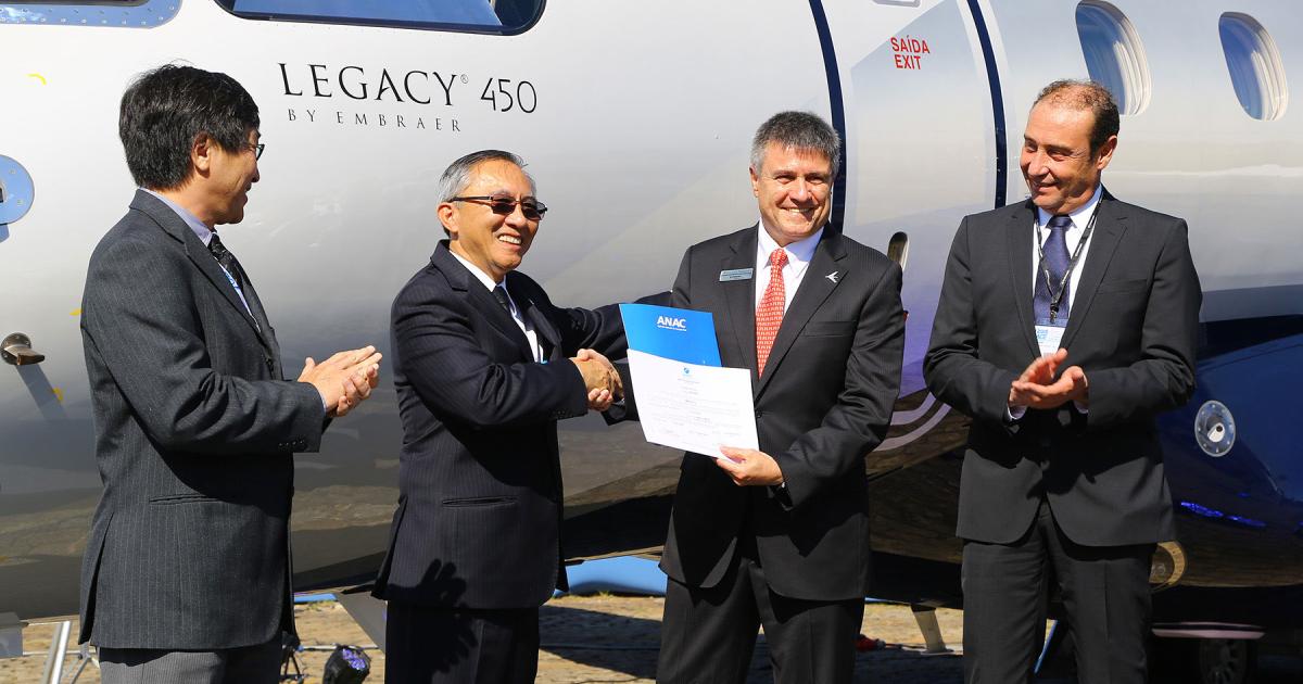 Embraer Executive Jets president and CEO Marco Túlio Pellegrini (center right) accepts certification papers for his company’s new Legacy 450 “mid-light” business jet from Brazil Agência Nacional de Aviação Civil (ANAC) deputy Dino Ishikura (center left). The pair are flanked by ANAC airworthiness superintendent Mario Igawa (far left) and Embraer vice president of engineering and technology Humberto Pereira (far right).
